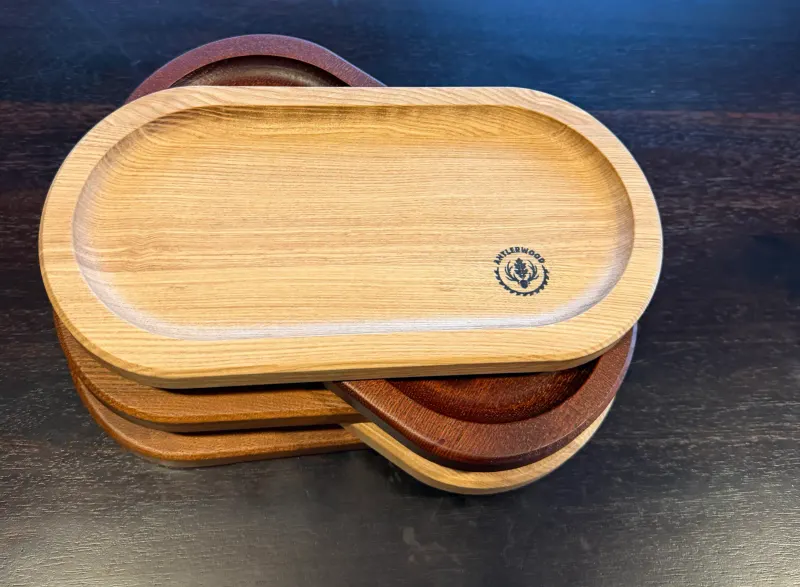 Stoh oválnych drevených tácok v rôznych odtieňoch, vrchná tácka s logom Antlerwood